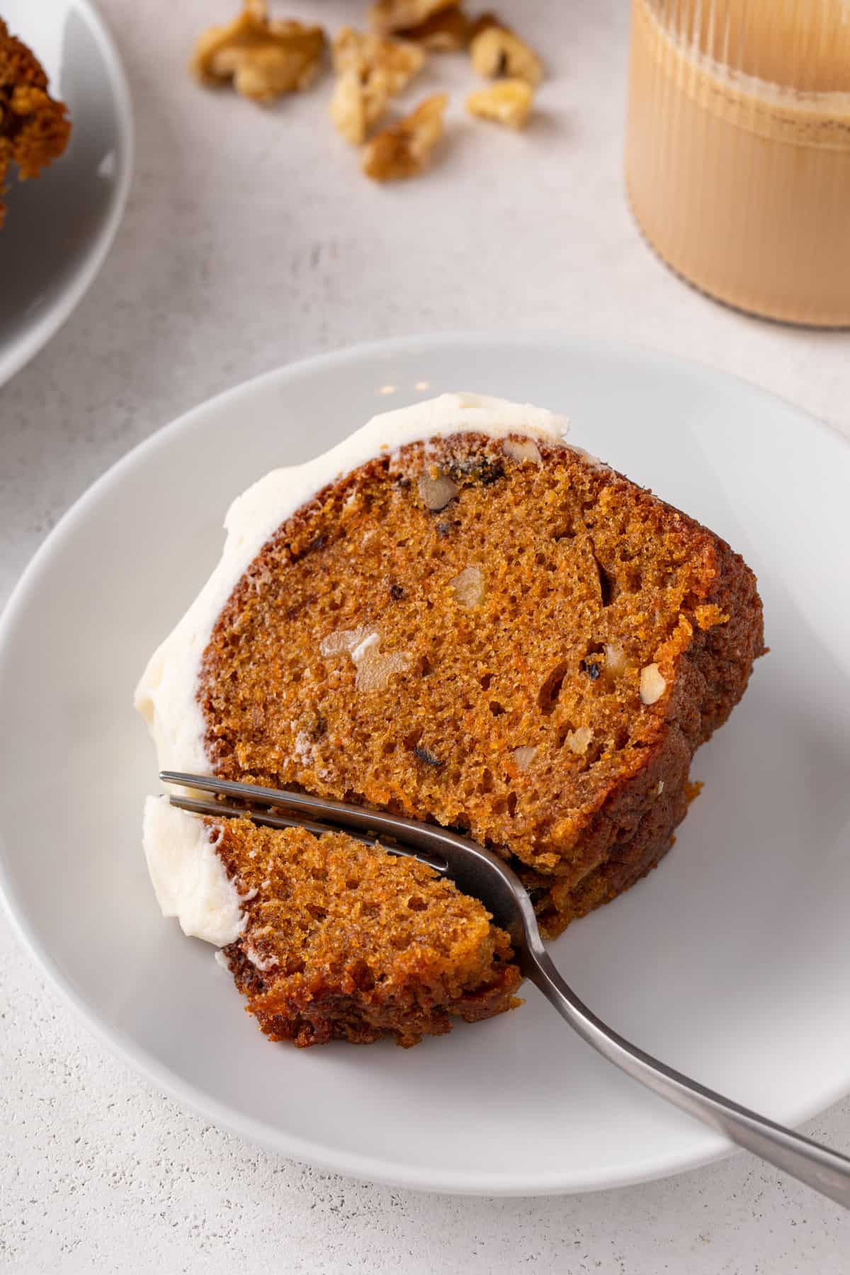 Fork cutting into a slice of carrot bundt cake on a white plate.