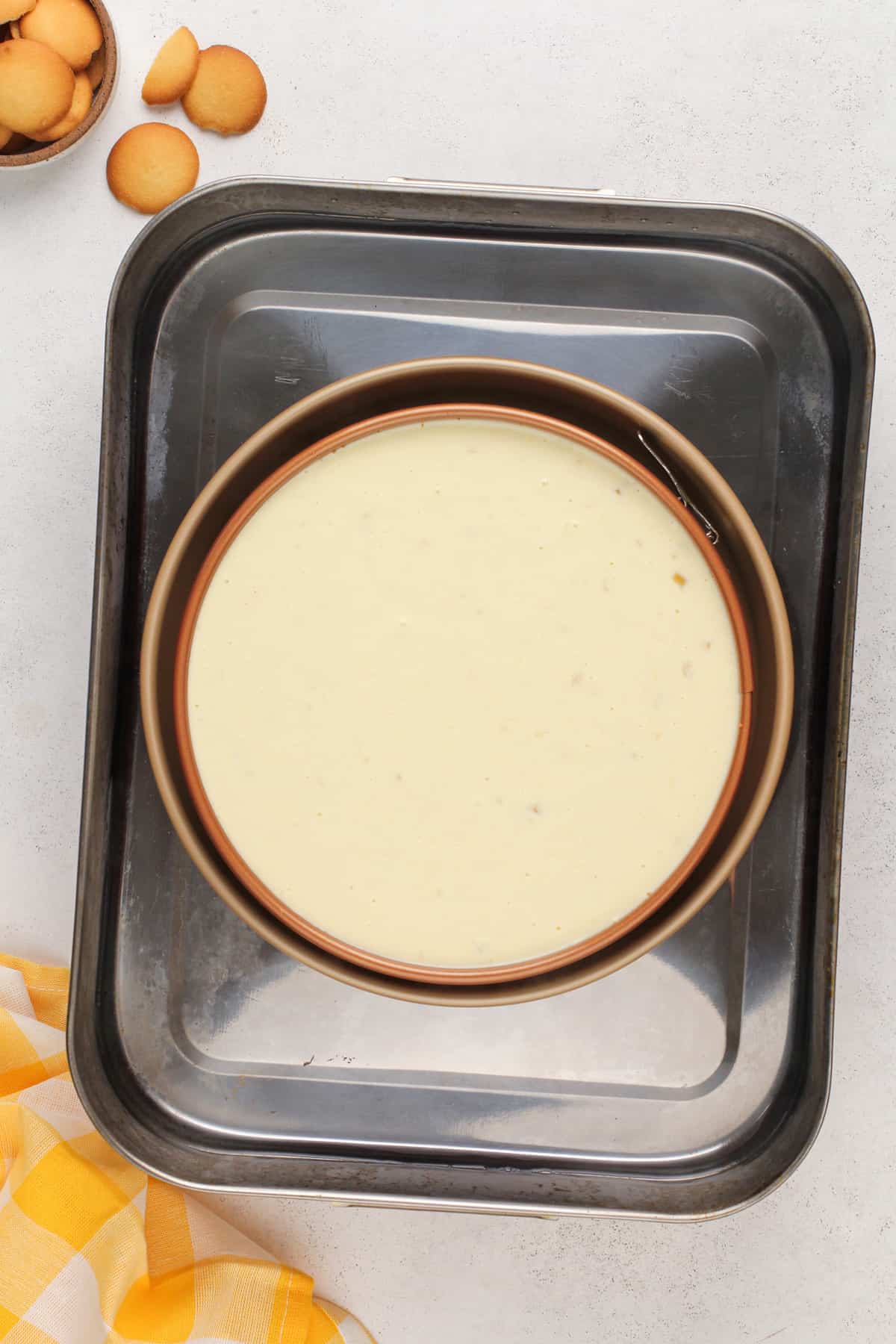 Unbaked banana pudding cheesecake in a water bath in a roasting pan, ready to go in the oven.