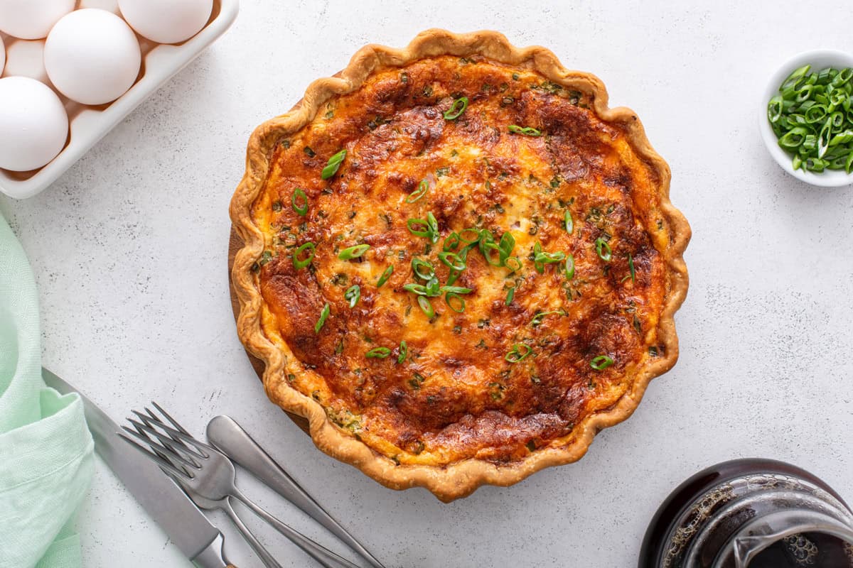 Baked and cooled ham and cheese quiche set on a countertop.