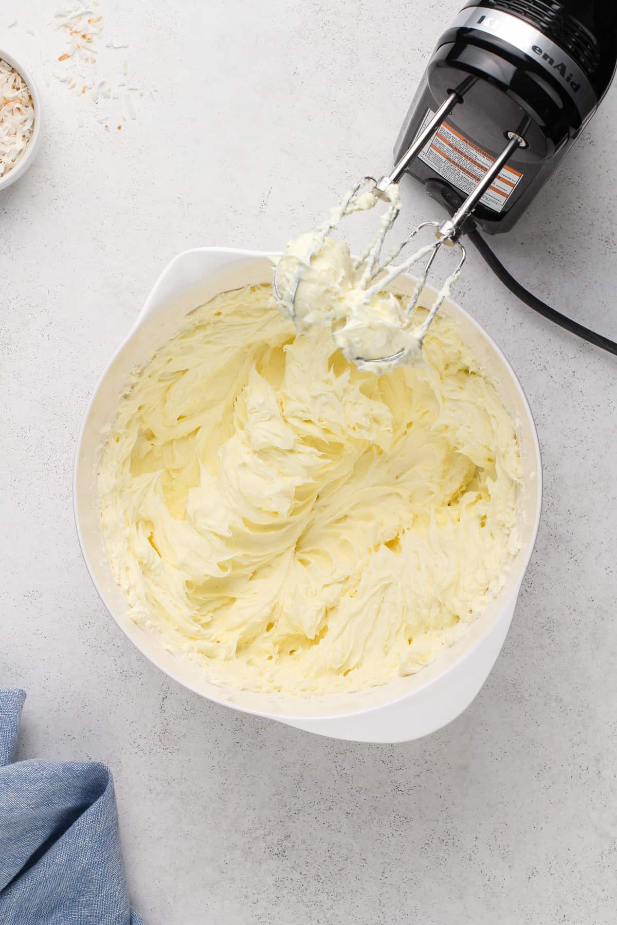 Cream cheese whipped with sugar in a white mixing bowl.