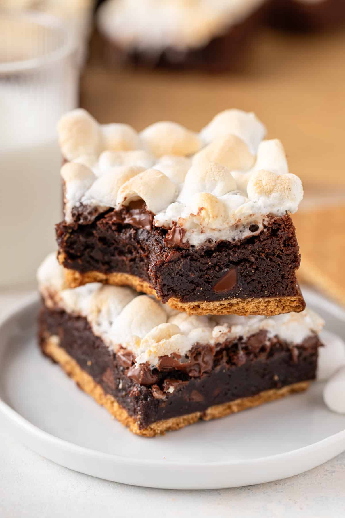 Two stacked easy s'mores brownies on a plate, with a bite taken from the corner of one brownie.