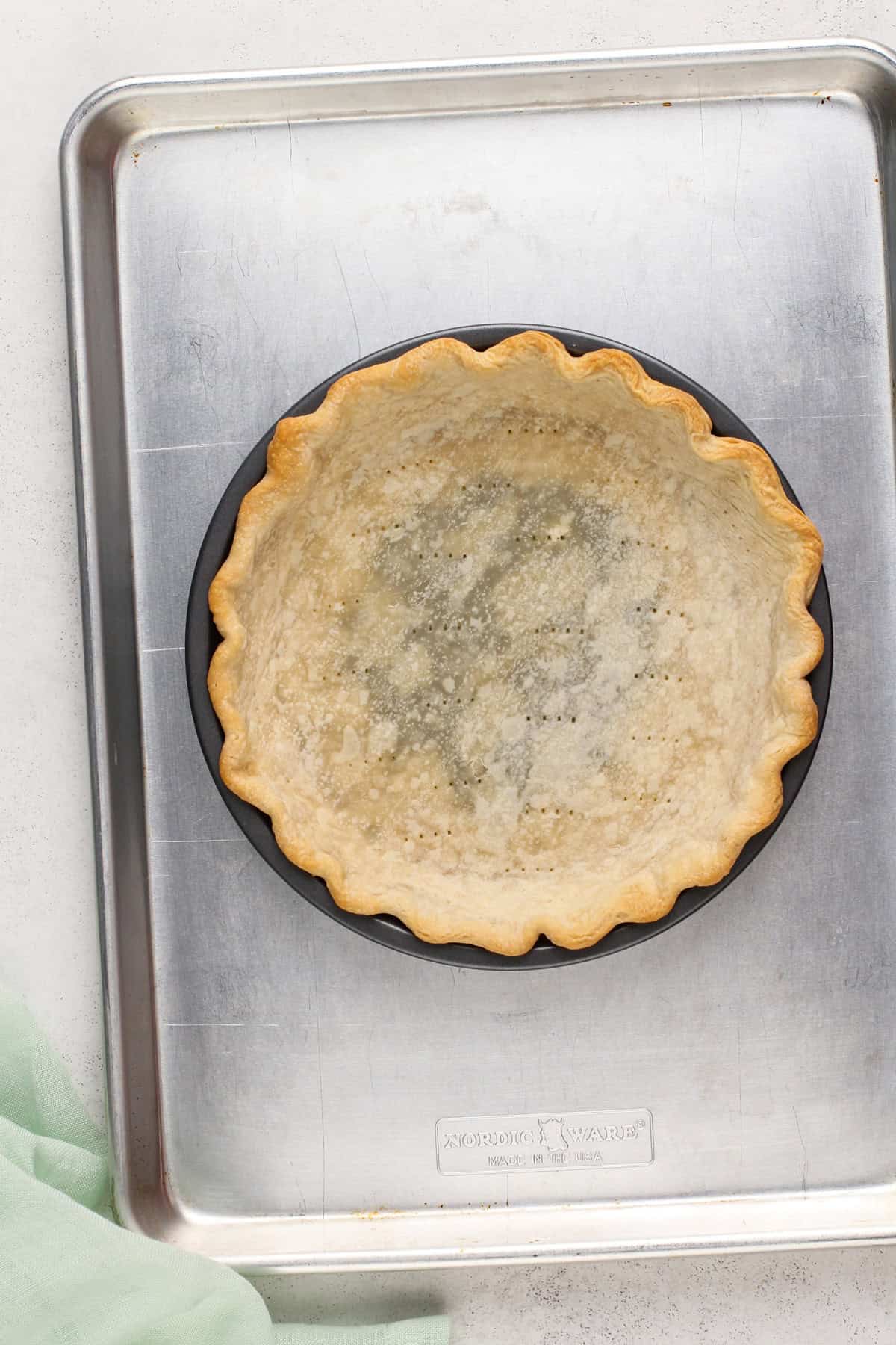 Blind baked pie crust set on a rimmed baking sheet.