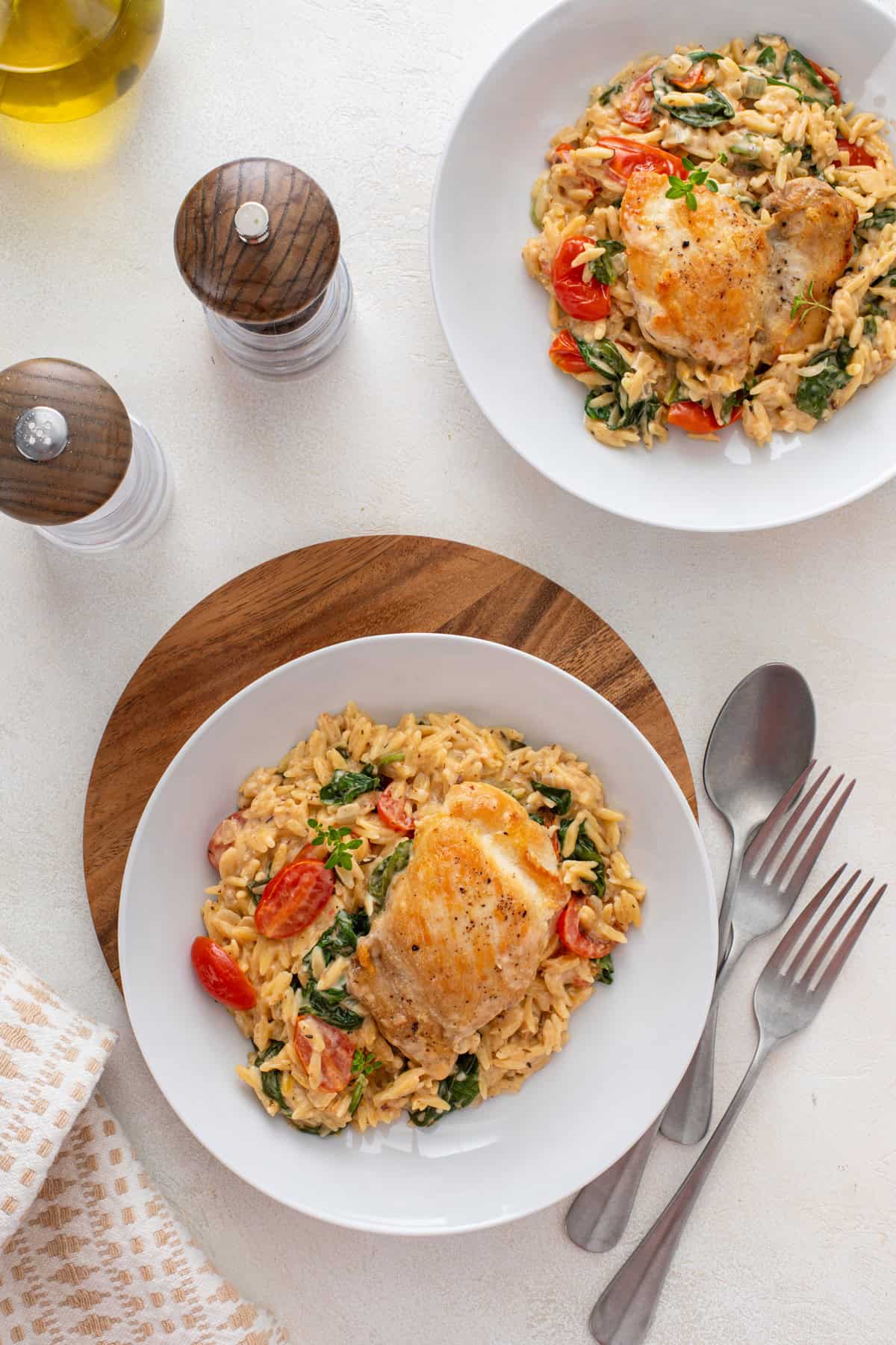 Overhead view of two white plates with lemon chicken and orzo.