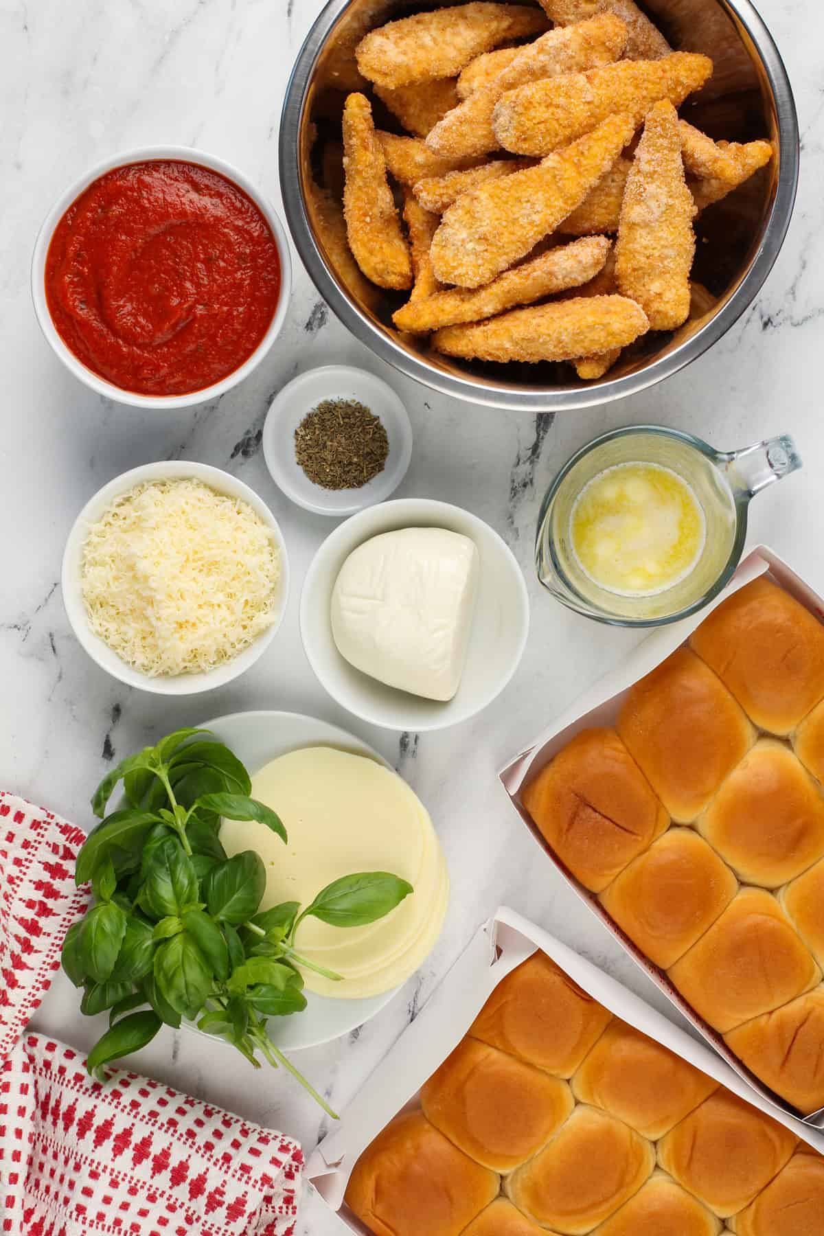 Chicken parmesan slider ingredients arranged on a white countertop.