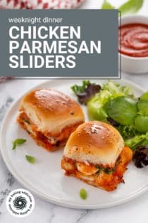 Two chicken parmesan sliders next to a green salad on a white plate. Text overlay includes recipe name.