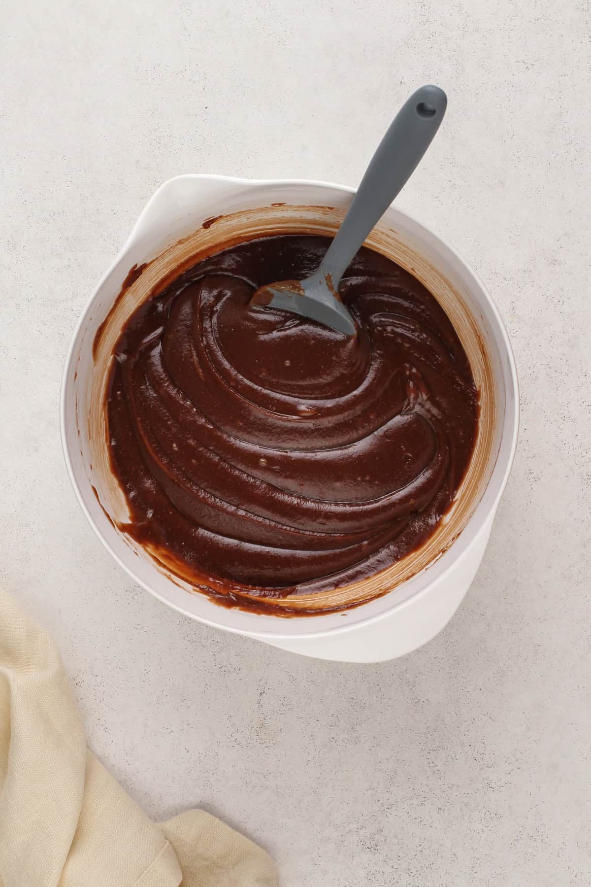 Chocolate mixture mixed with dry ingredients in a white bowl for texas sheet cake.