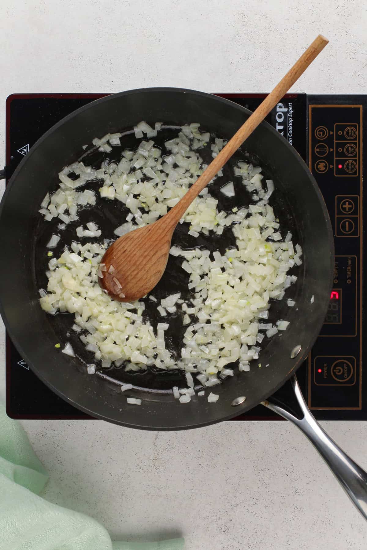 Onions being sautéed in a skillet.