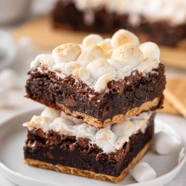 Two easy s'mores brownies stacked on a white plate.