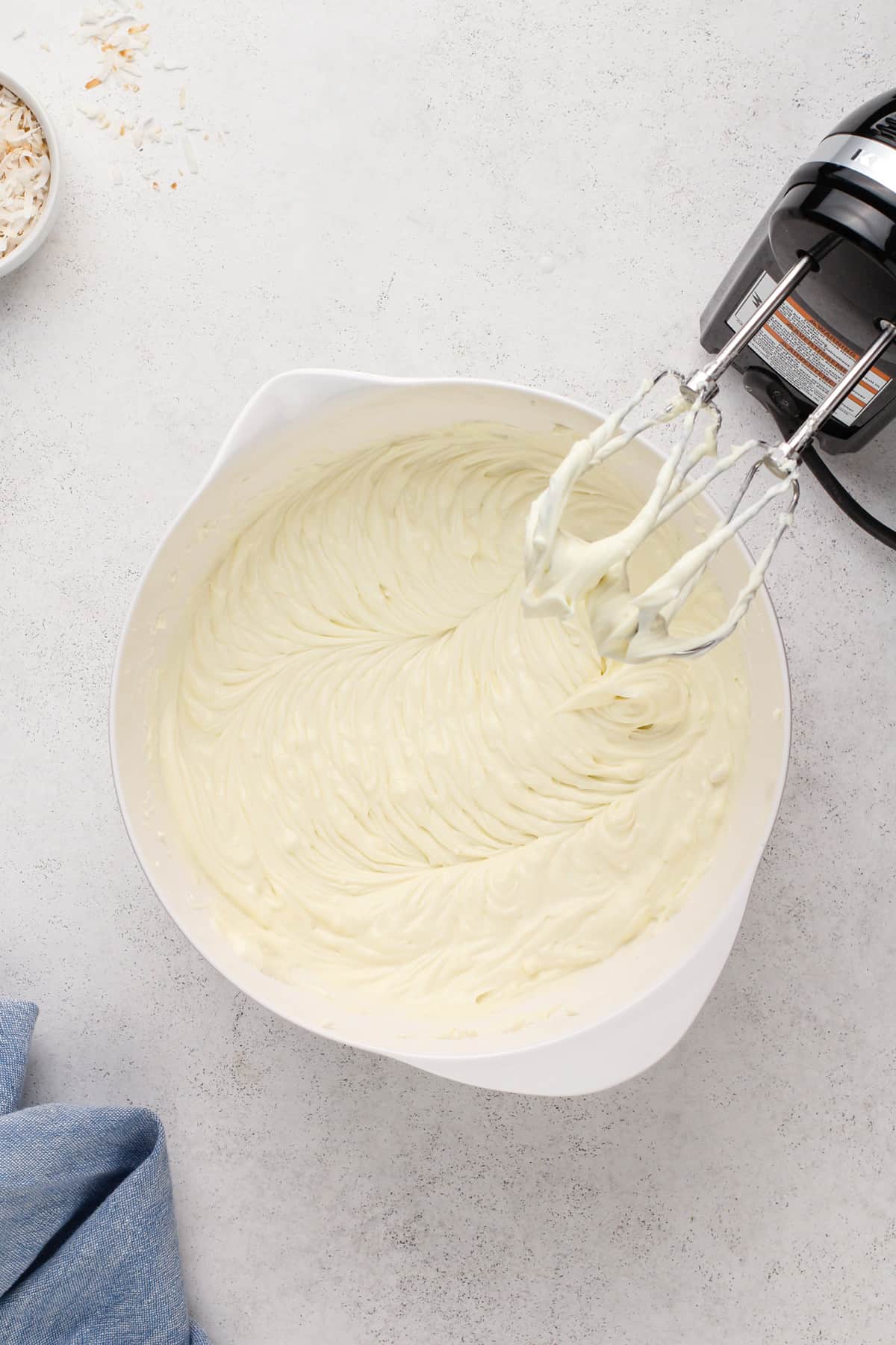 Coconut cheesecake filling in a white mixing bowl.