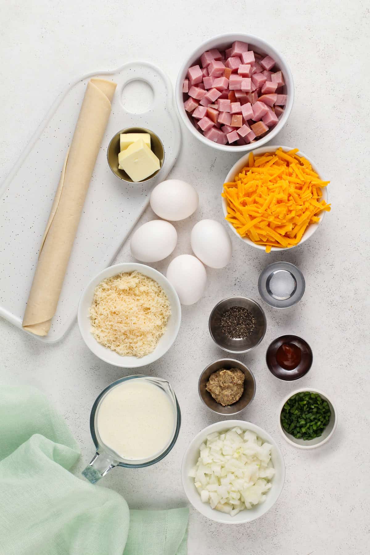 Ingredients for ham and cheese quiche arranged on a countertop.