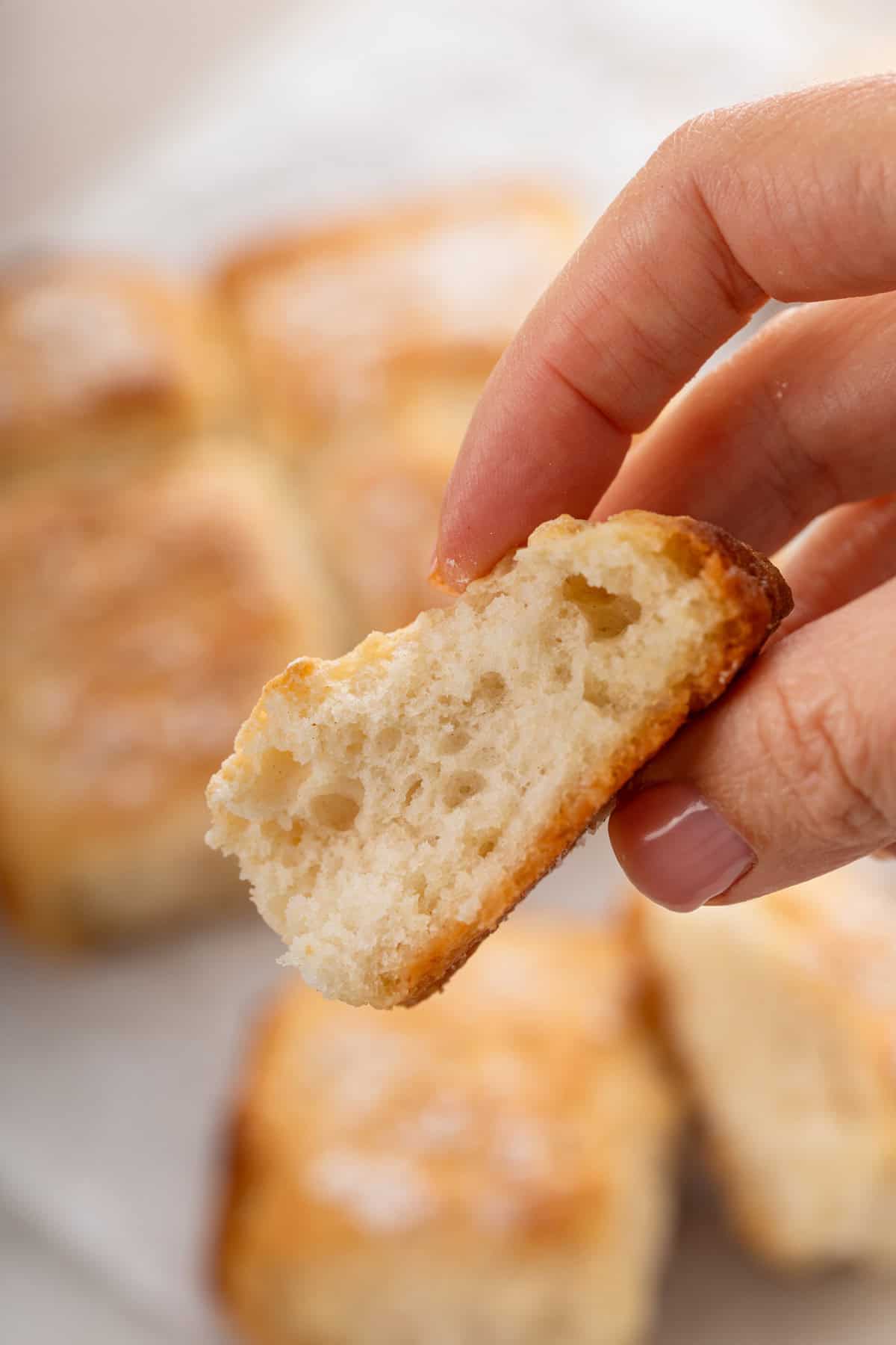 Hand holding part of a 7up biscuit up to the camera.