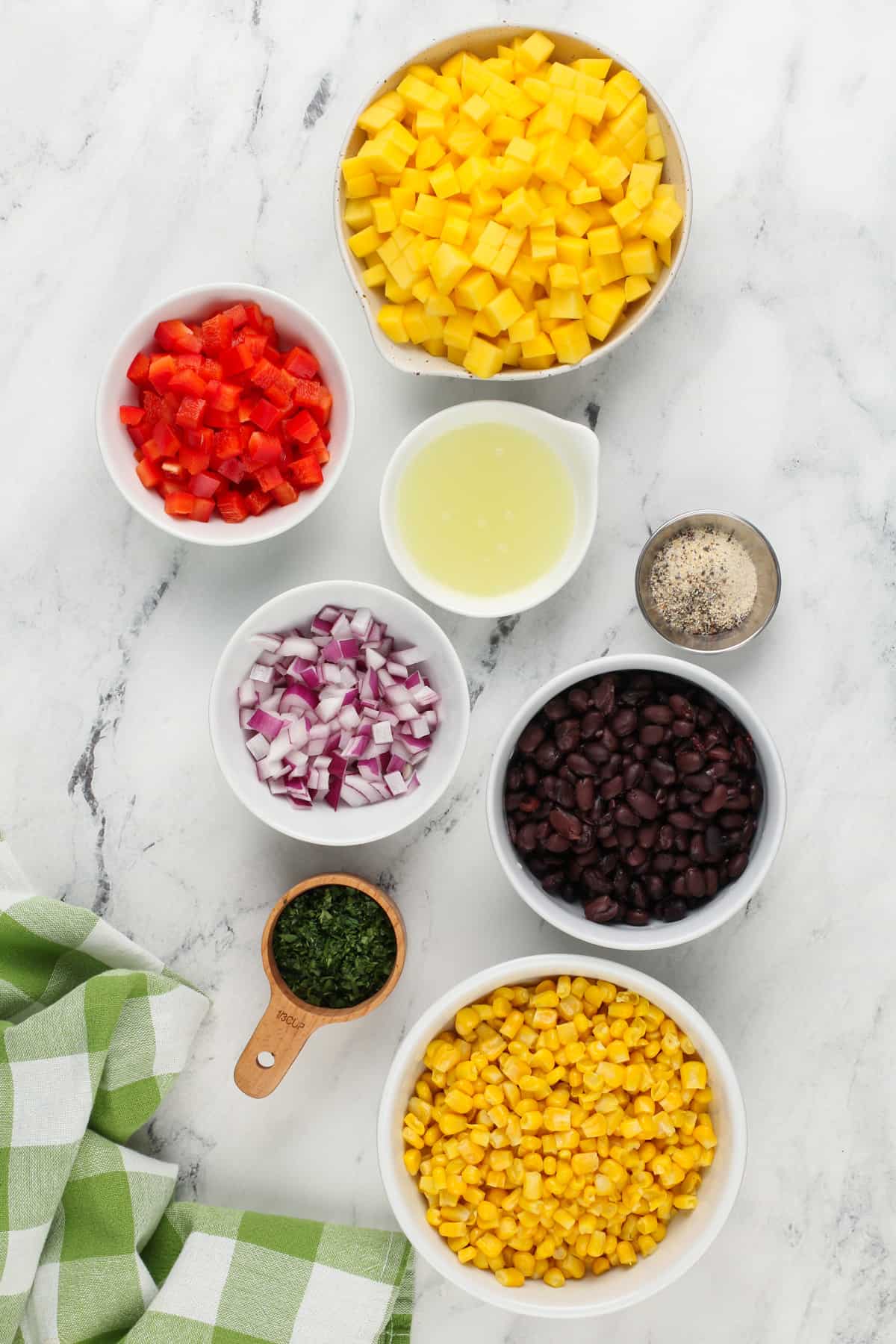 Ingredients for mango and black bean salsa arranged on a mango countertop.