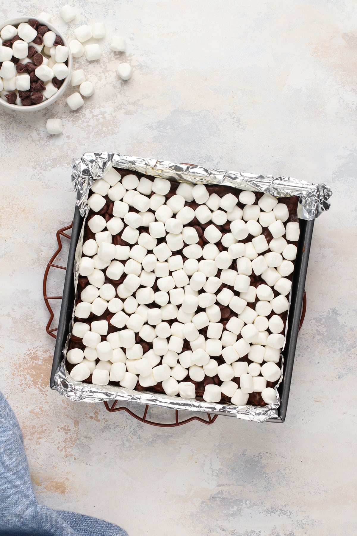 Chocolate chips and mini marshmallows sprinkled on brownies, ready to go in the oven.