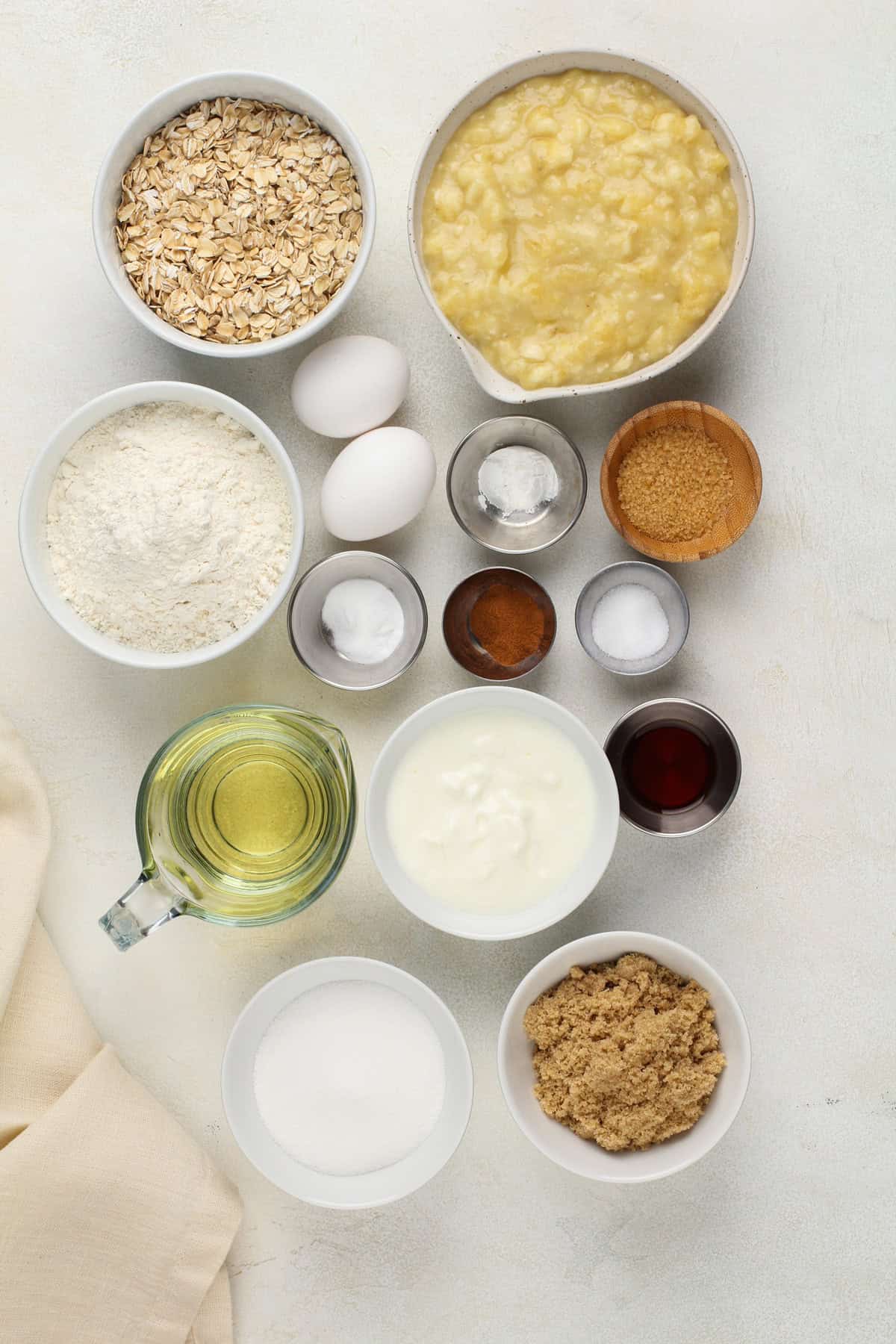 Ingredients for oatmeal banana bread arranged on a light-colored countertop.