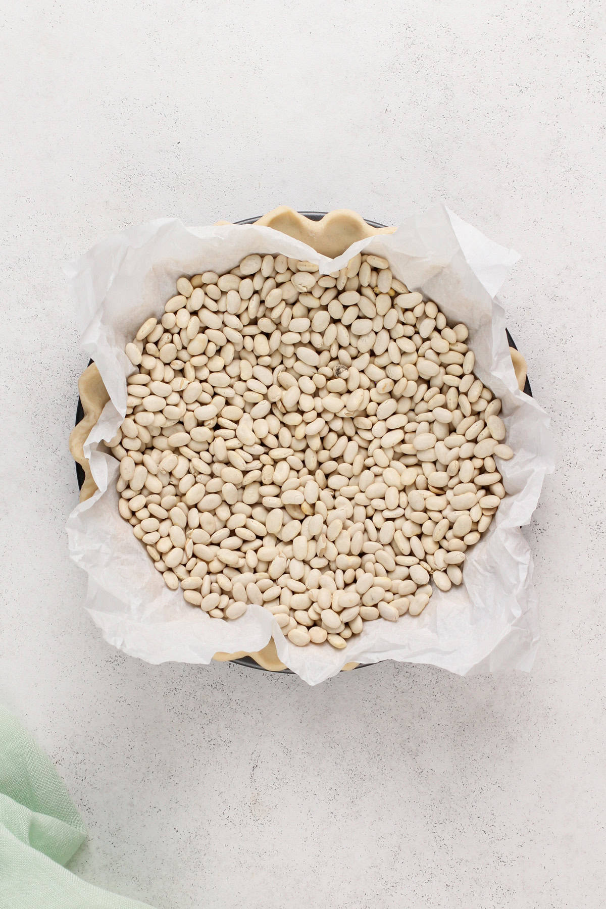Dry beans in a parchment-lined pie crust for blind baking.