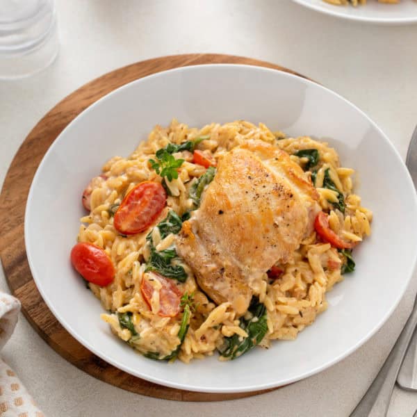 Serving of one-pot lemon chicken and orzo on a white plate.