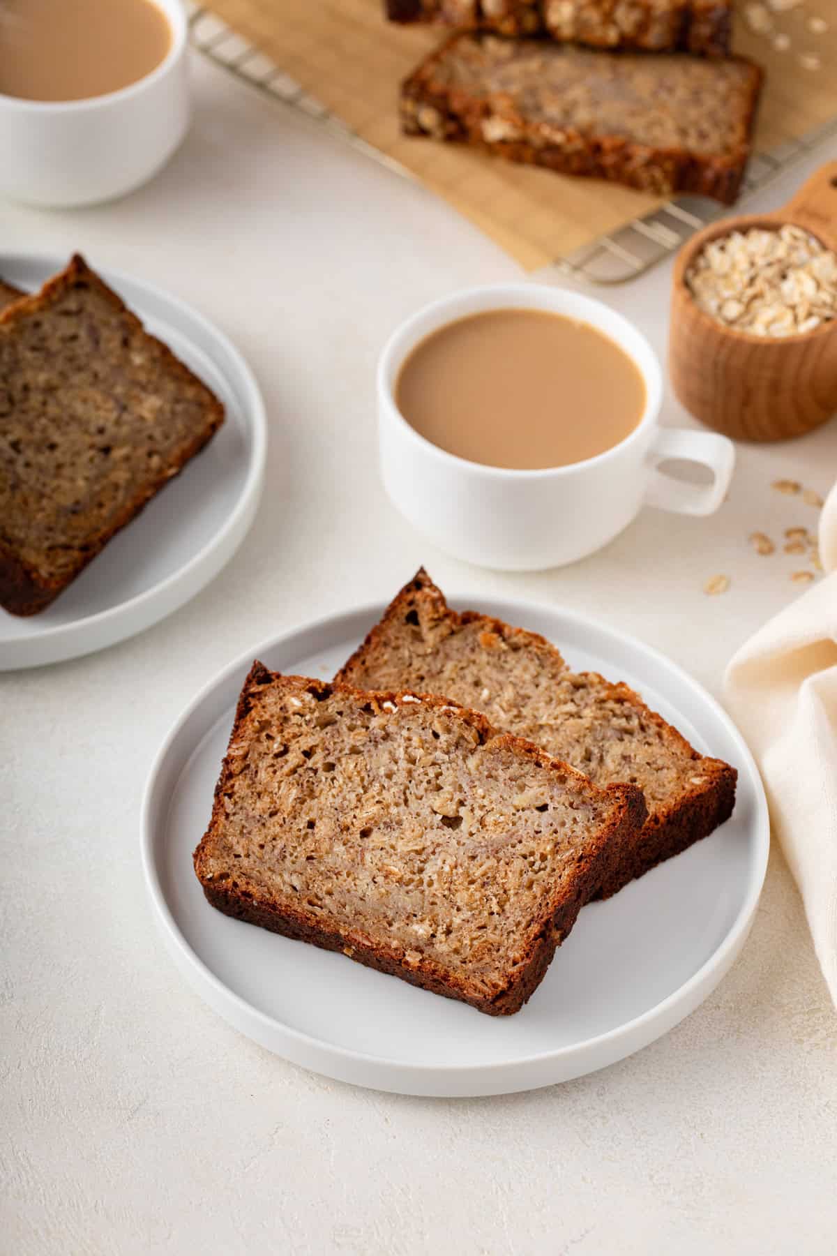 Two plates, each with slices of oatmeal banana bread, next to a cup of coffee.