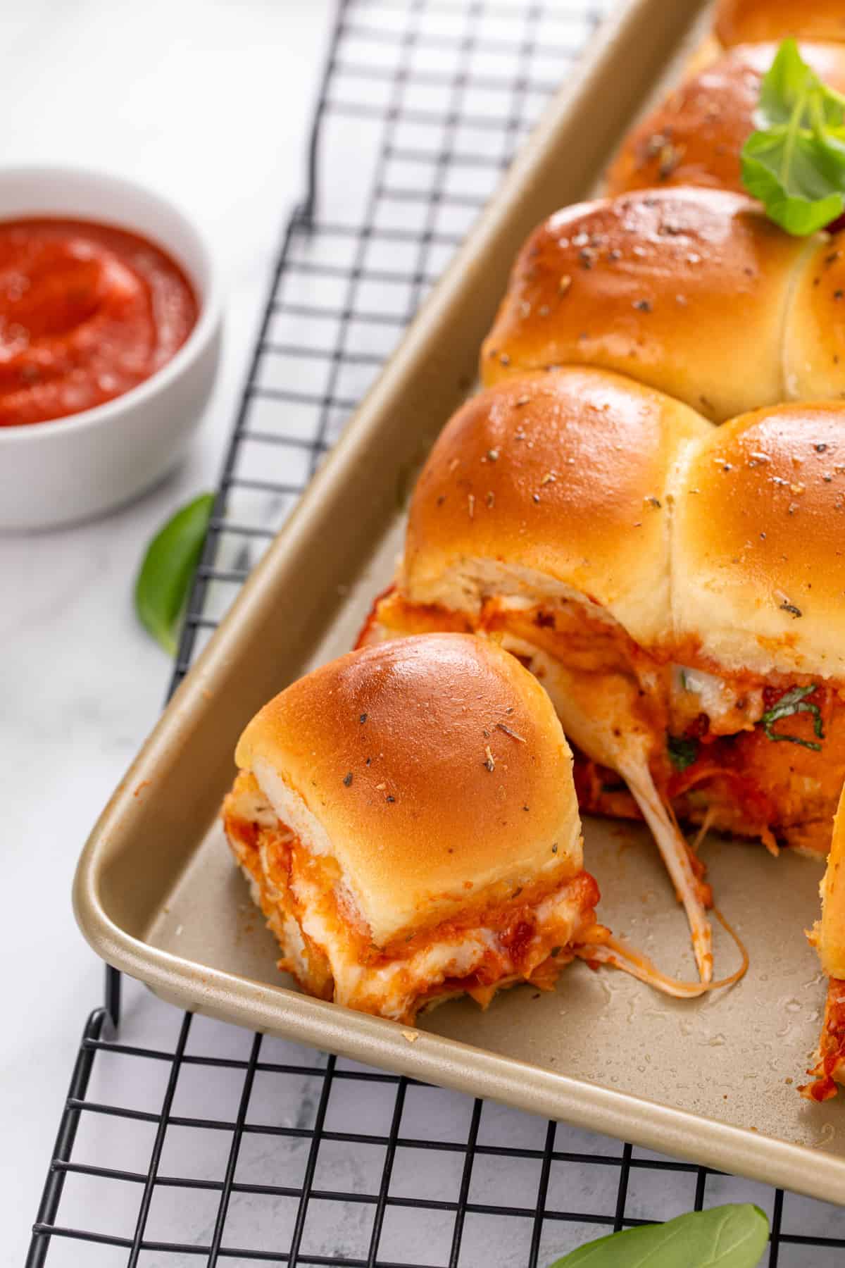 Chicken parmesan slider cut from the pan of sliders and being pulled away.
