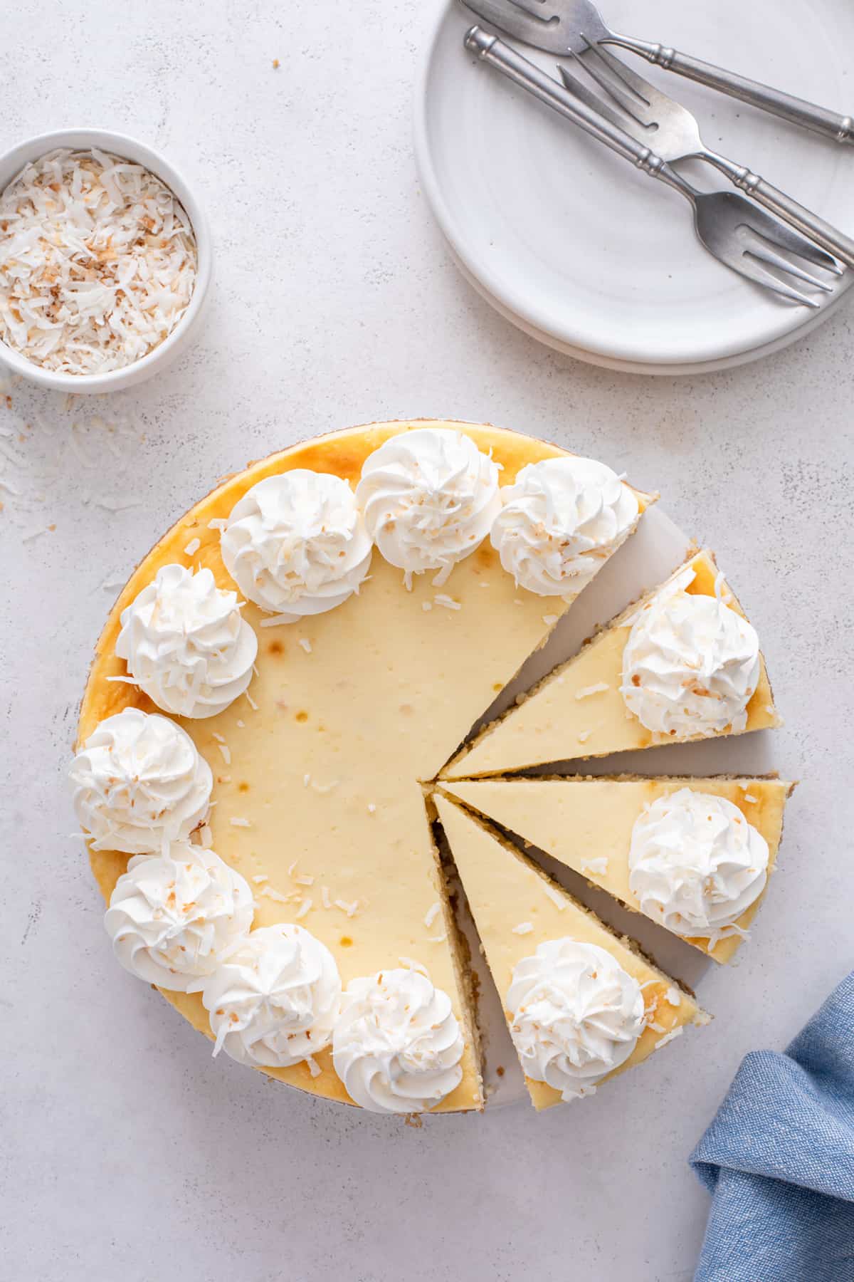 Overhead view of sliced coconut cheesecake garnished with whipped cream.