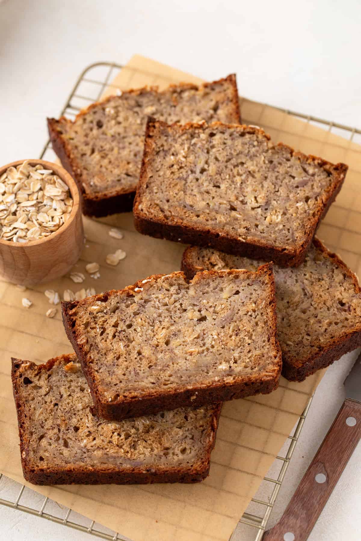 Several slices of oatmeal banana bread arranged on a wire cooling rack.