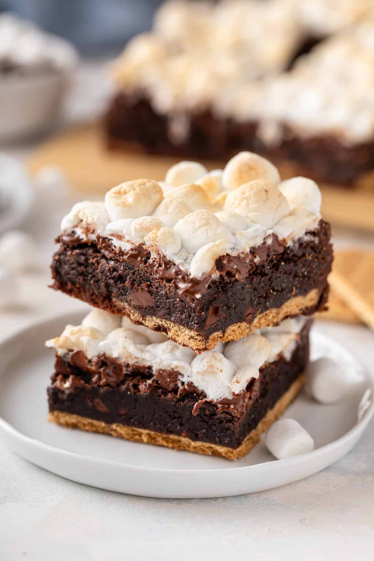 Two easy s'mores brownies stacked on a white plate.