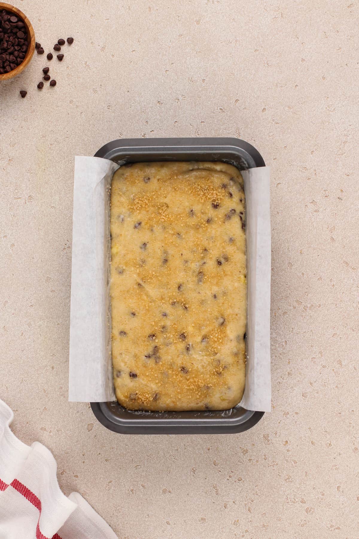 Unbaked chocolate chip banana bread in a parchment-lined loaf pan, ready to go in the oven.