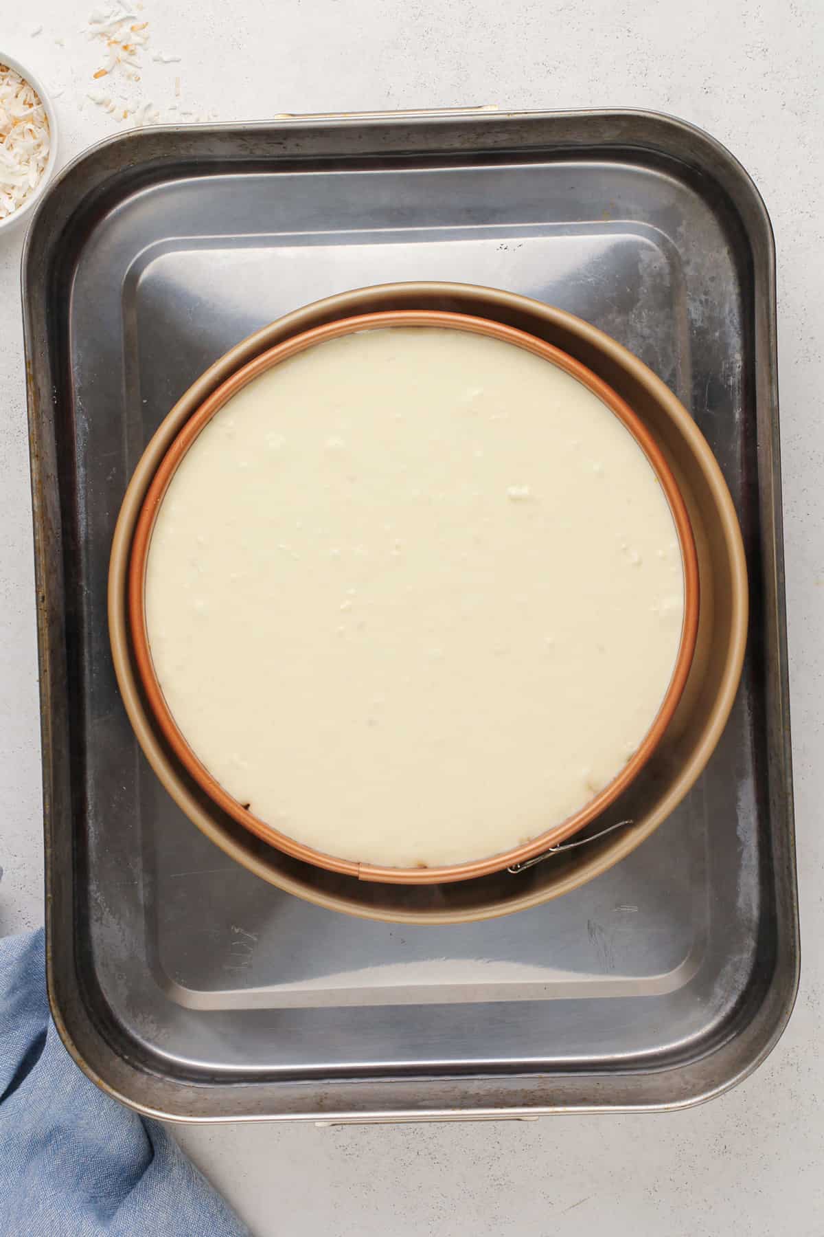 Unbaked coconut cheesecake in a water bath.