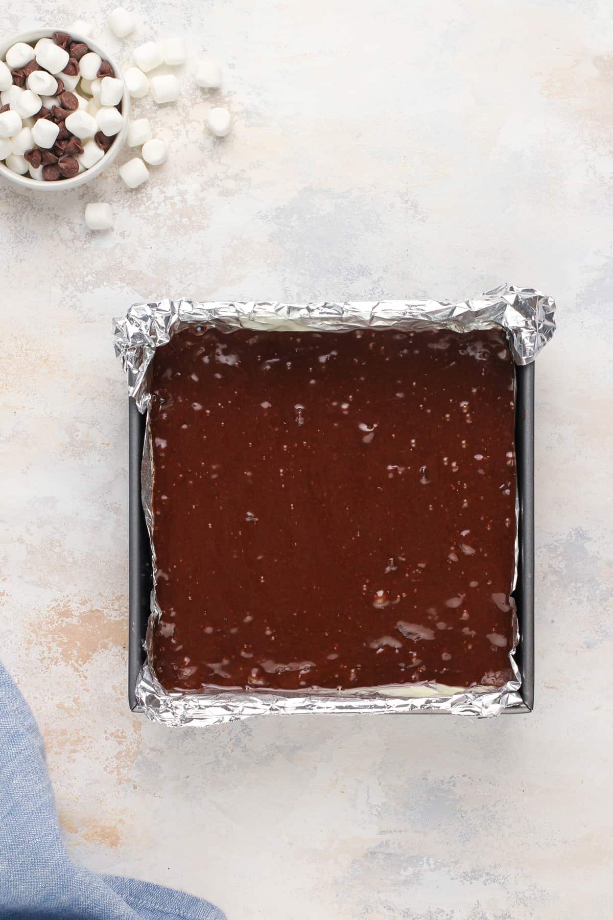 Brownie batter poured over graham crackers in a baking pan, ready to go in the oven.