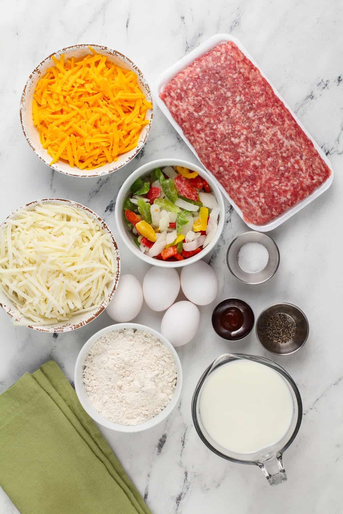 Ingredients for bisquick breakfast casserole arranged on a marble countertop.