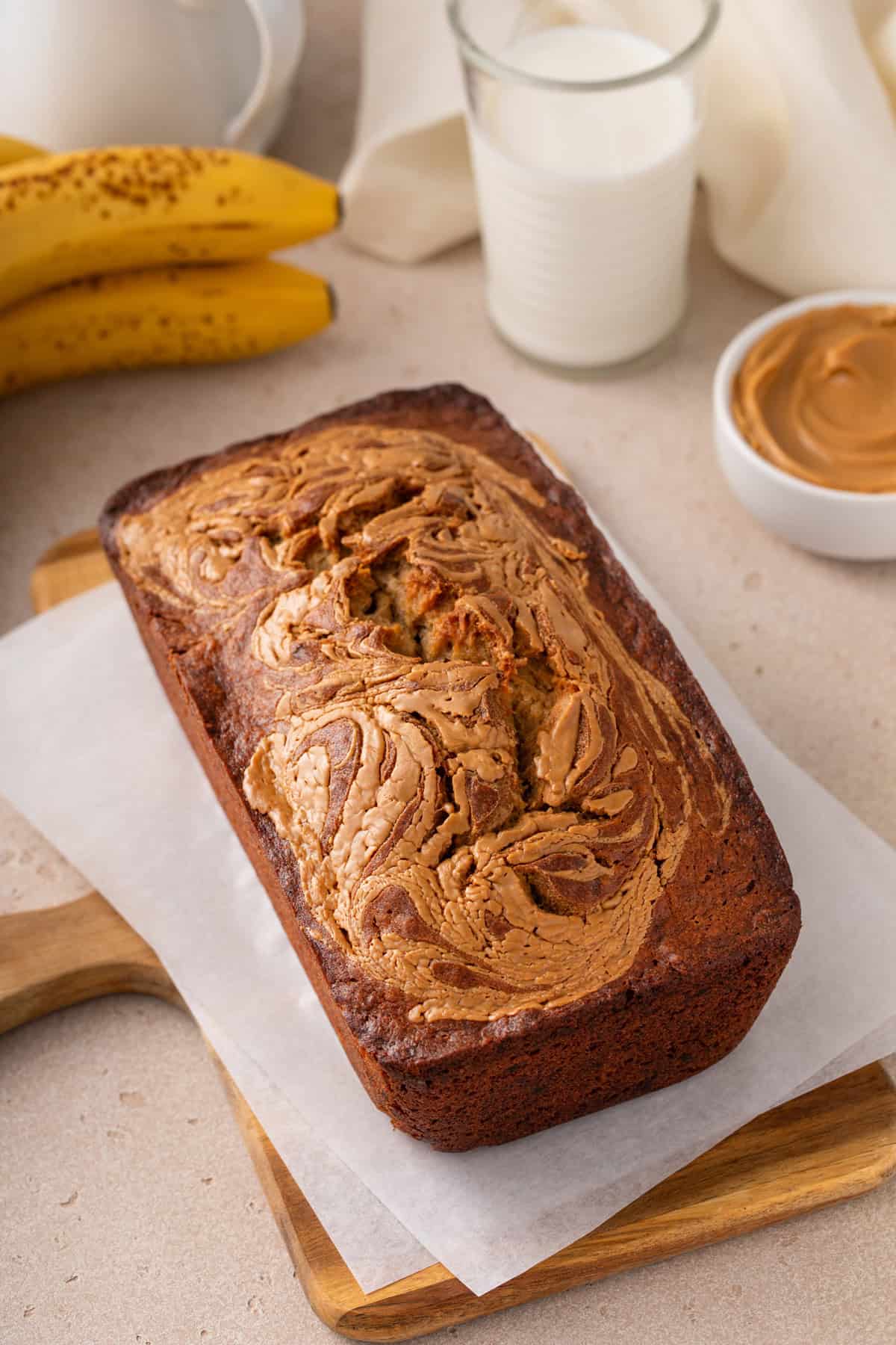 Cooled loaf of peanut butter banana bread set on a piece of parchment paper.