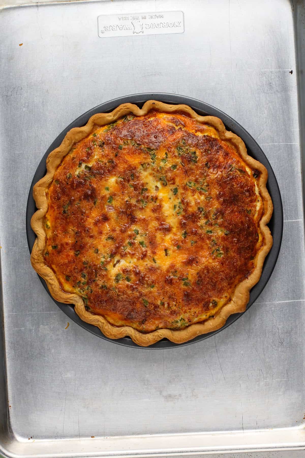 Baked quiche cooling on a rimmed baking sheet.