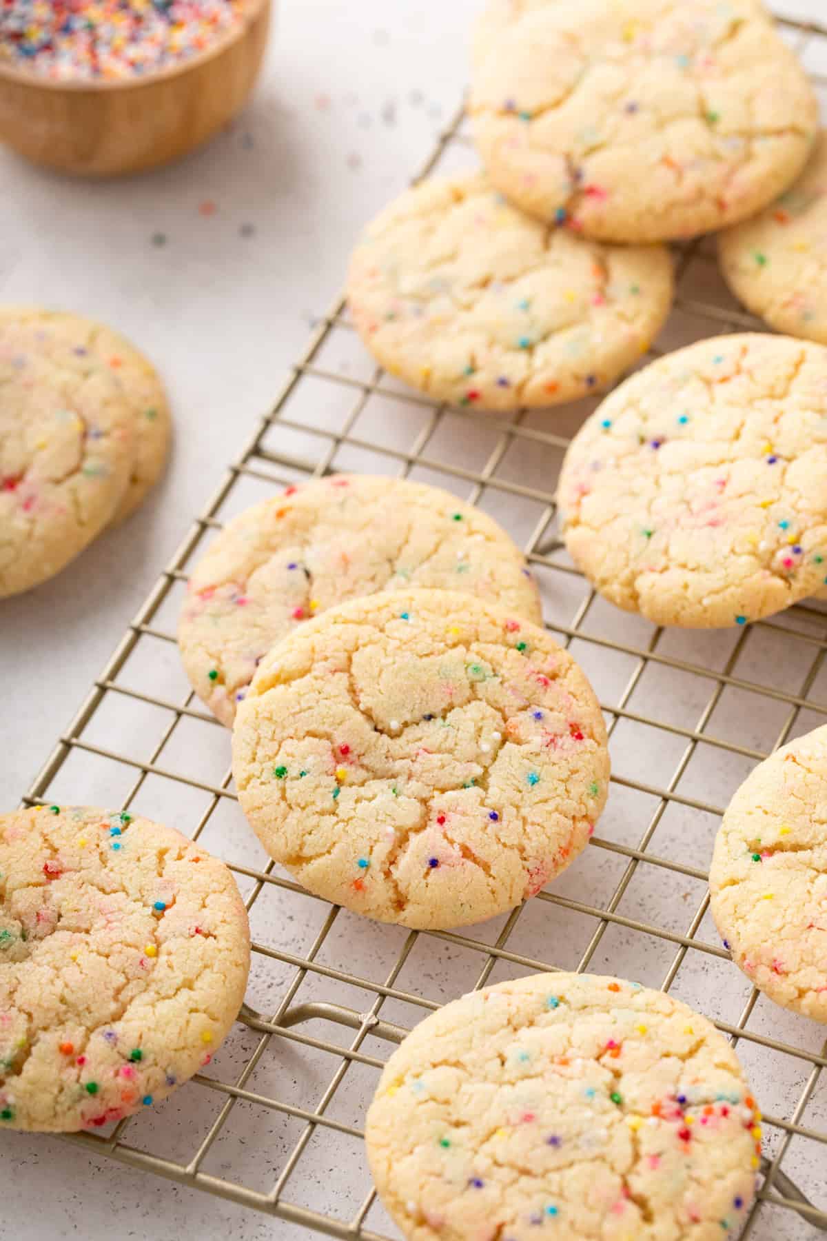 Easy sugar cookies with nonpareil sprinkles arranged on a wire rack.