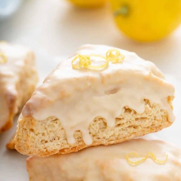 Close up of a glazed lemon scone stacked on top of a second scone.