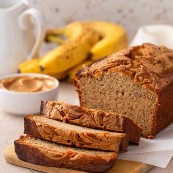 Sliced loaf of peanut butter banana bread set on a wooden board.