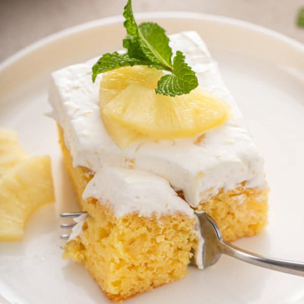 Fork cutting a bite from the corner of a slice of easy pineapple cake.