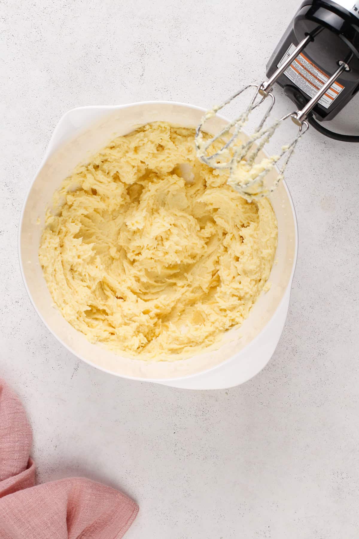 Butter, sugar, and eggs mixed together in a white mixing bowl.