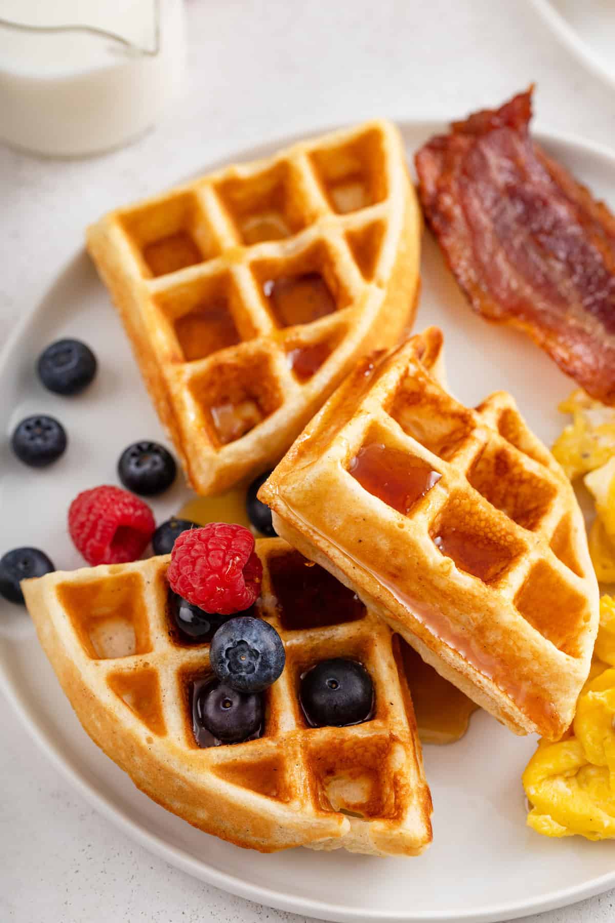Close up of homemade waffles topped with berries on a white plate.