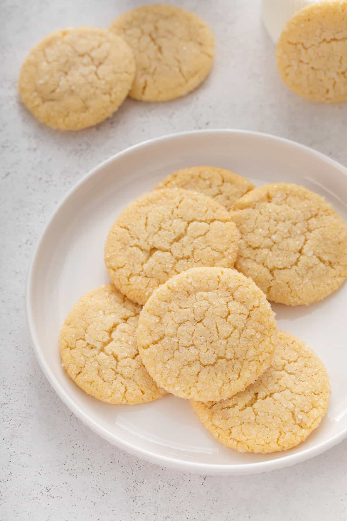 easy sugar cookies rolled in granulated sugar arranged on a white plate.