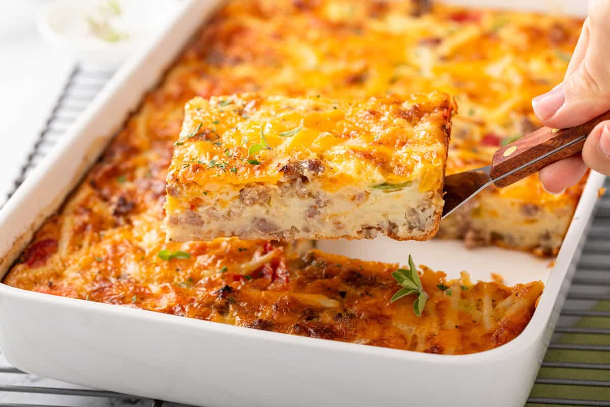 Metal spatula holding up a slice of bisquick breakfast casserole above a casserole dish.