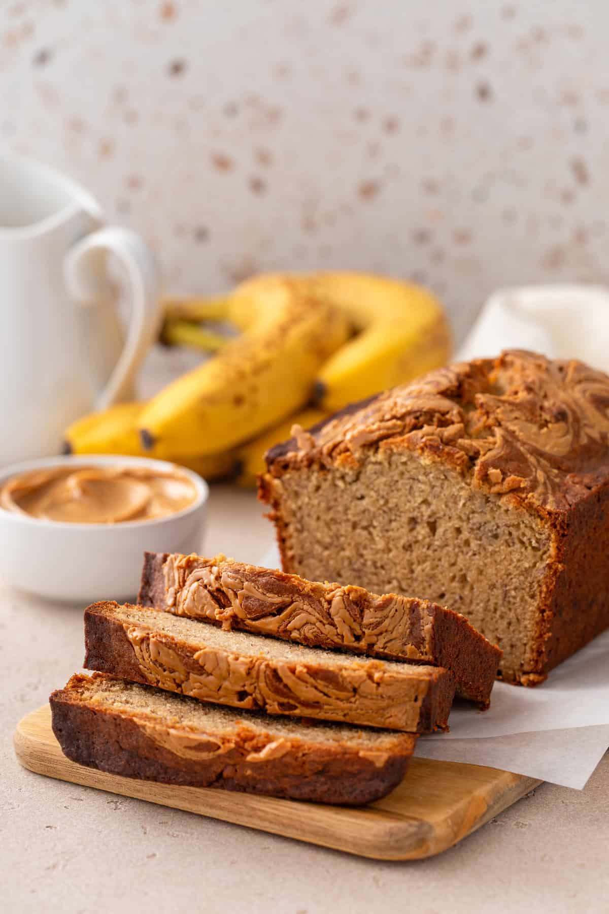Sliced loaf of peanut butter banana bread set on a wooden board.