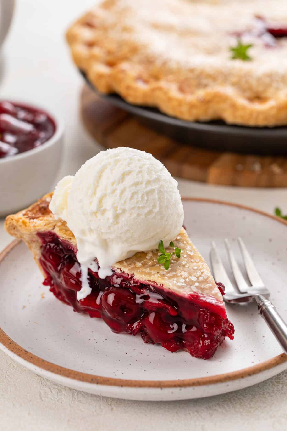 Slice of sour cherry pie a la mode on a plate.