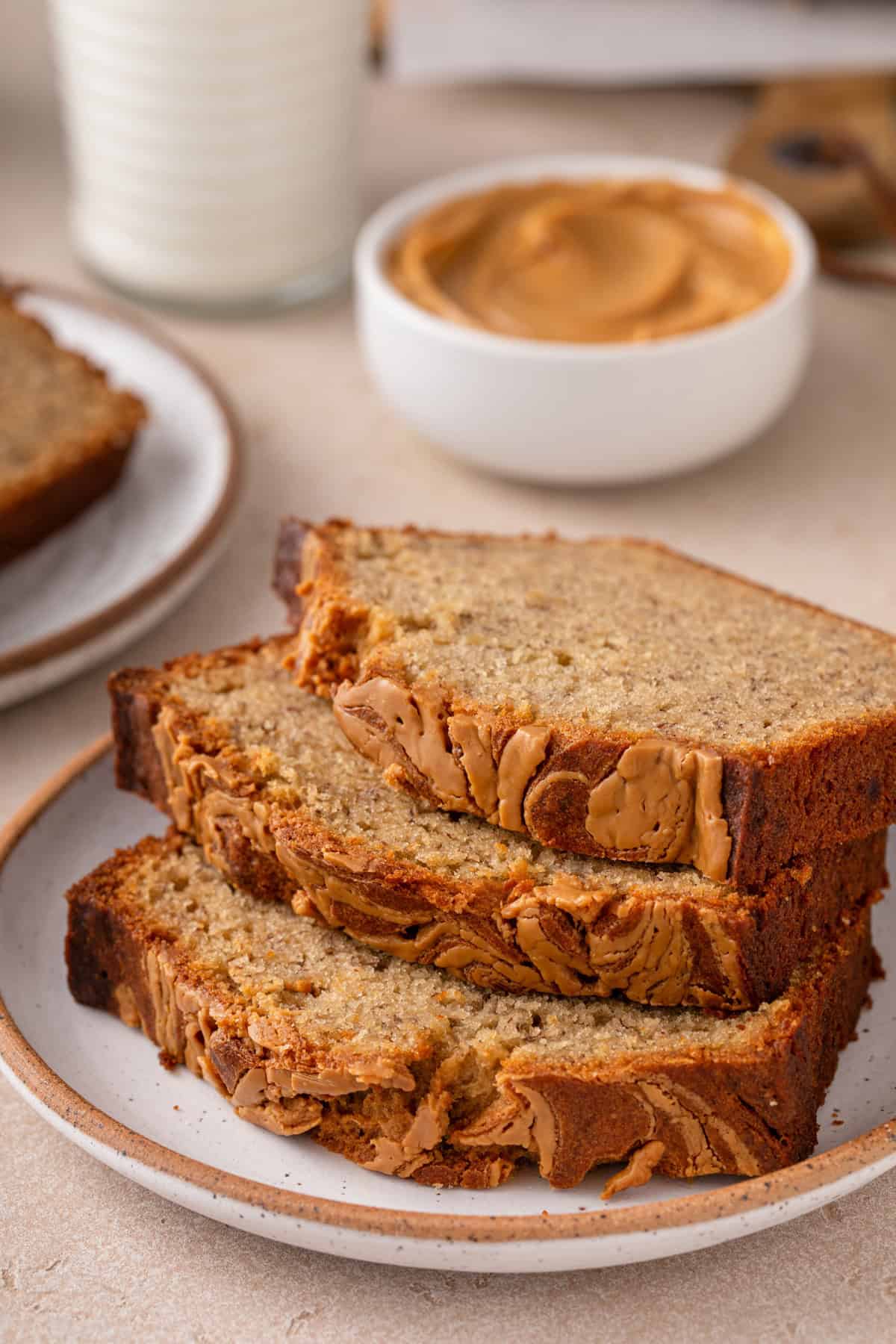 Three slices of peanut butter banana bread stacked on a plate.