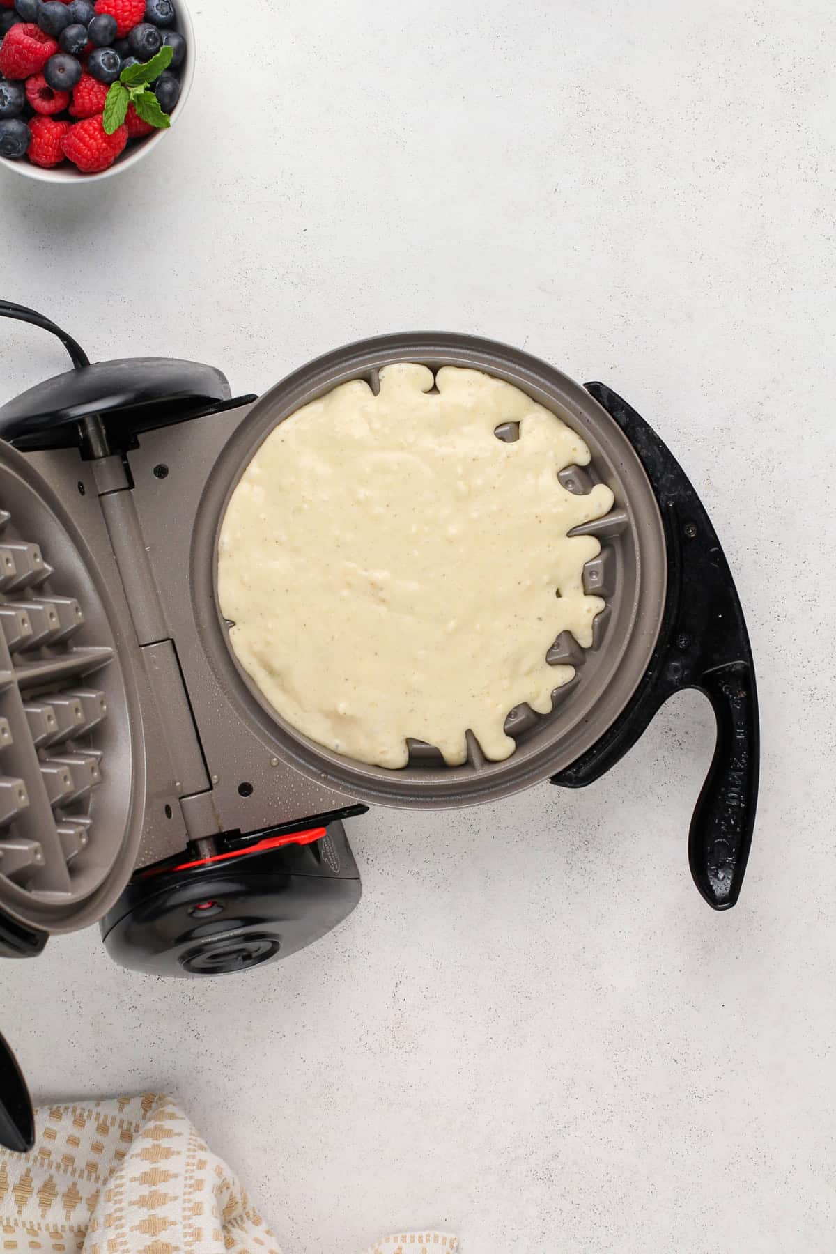 Homemade waffle batter in a waffle iron.