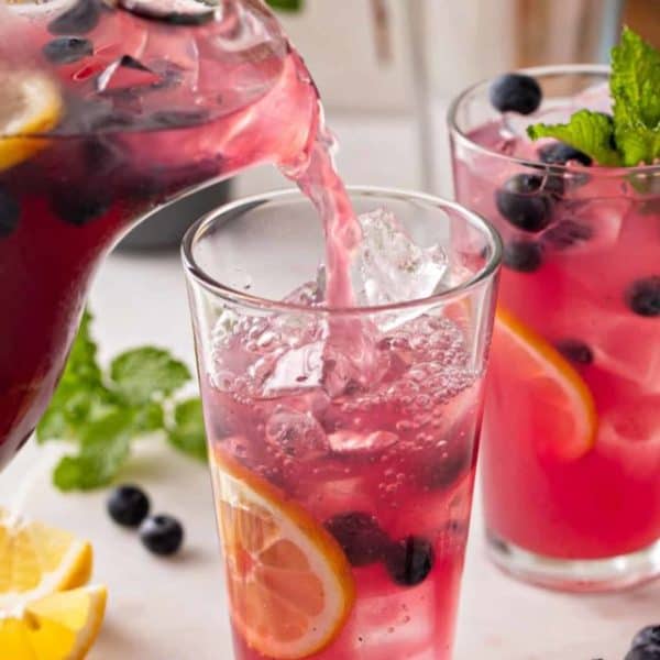 Blueberry lemonade being poured into a glass.