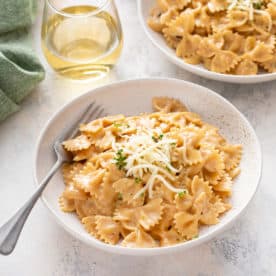 White bowl filled with french onion pasta and topped with cheese.