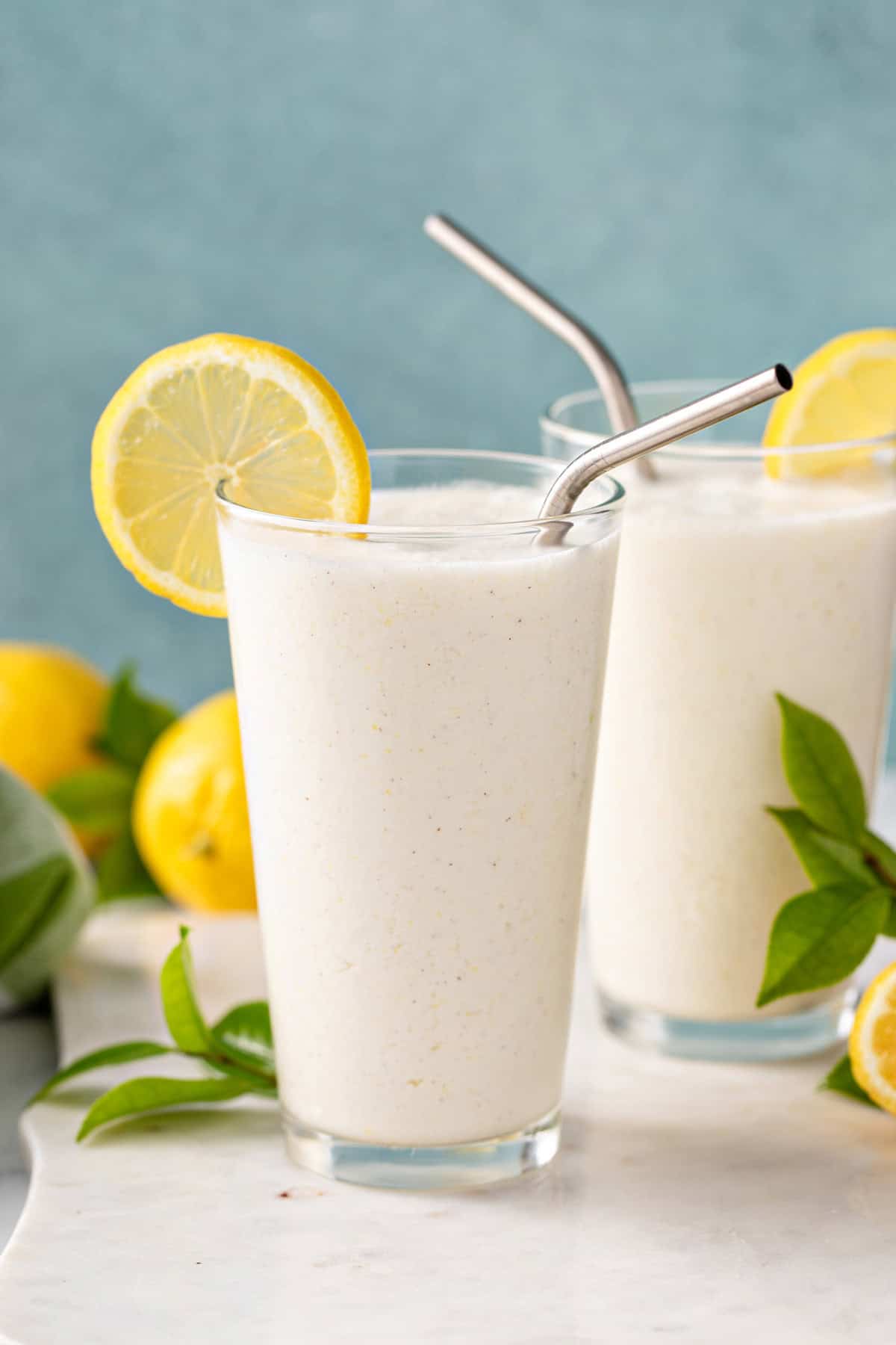 Close up of a glass of frosted lemonade on a marble countertop.