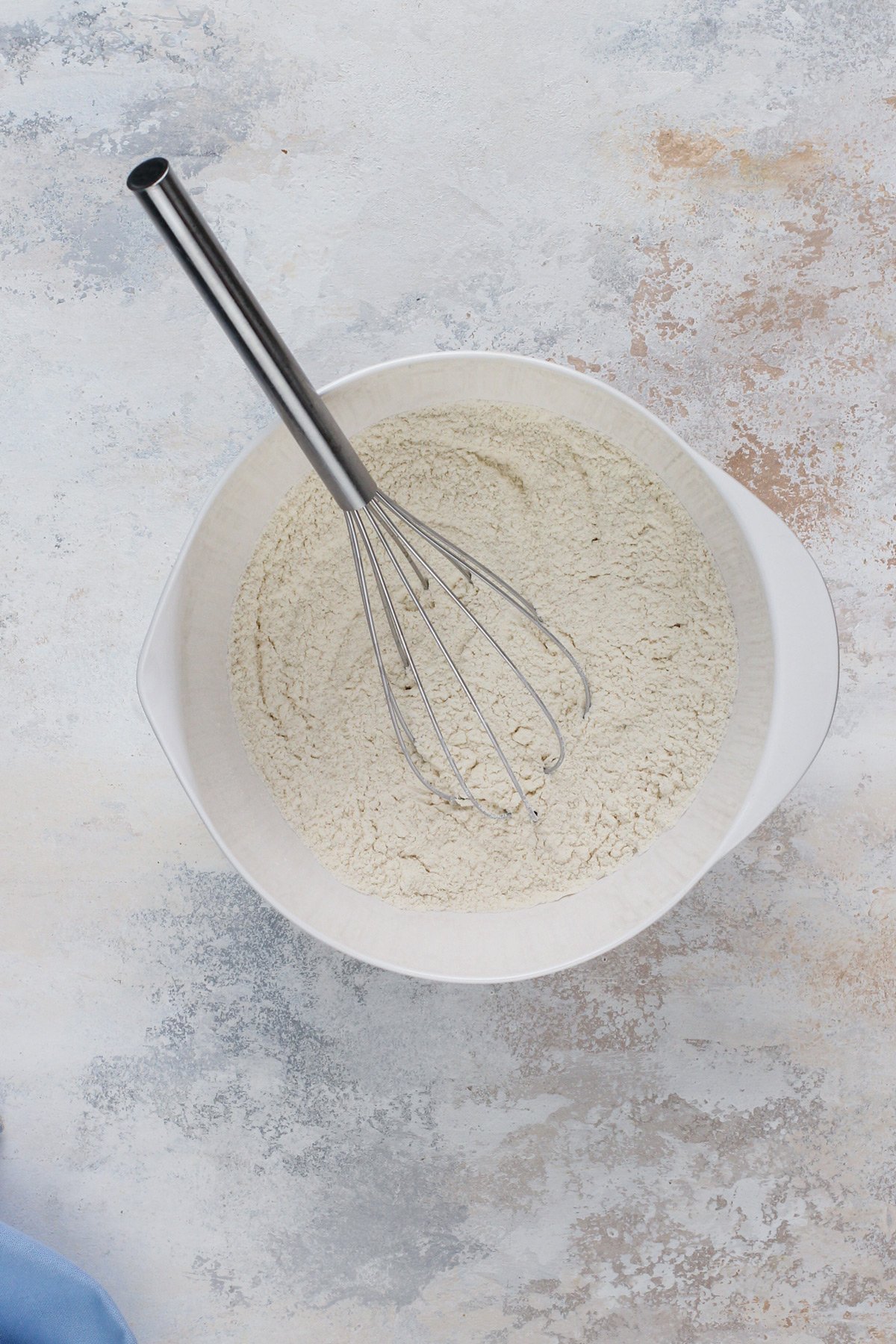 Dry ingredients for chocolate chip cookie cake whisked in a white bowl.