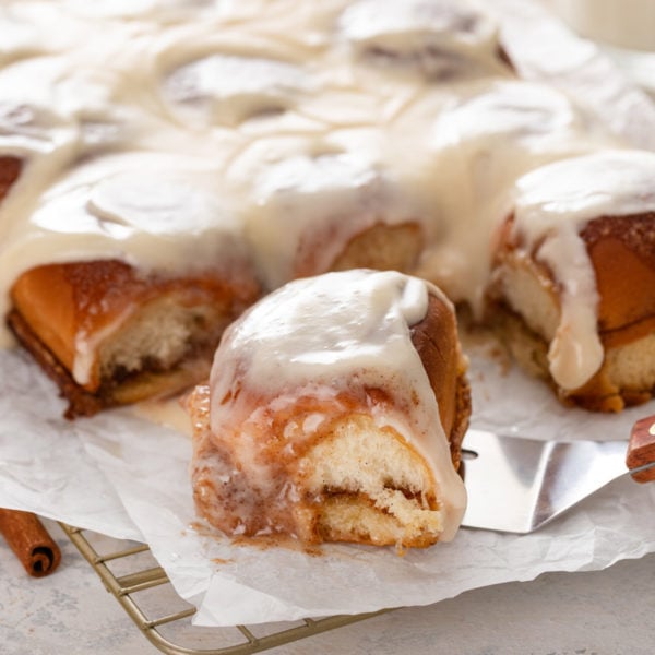 Cake server about to lift a hawaiian roll cinnamon roll.