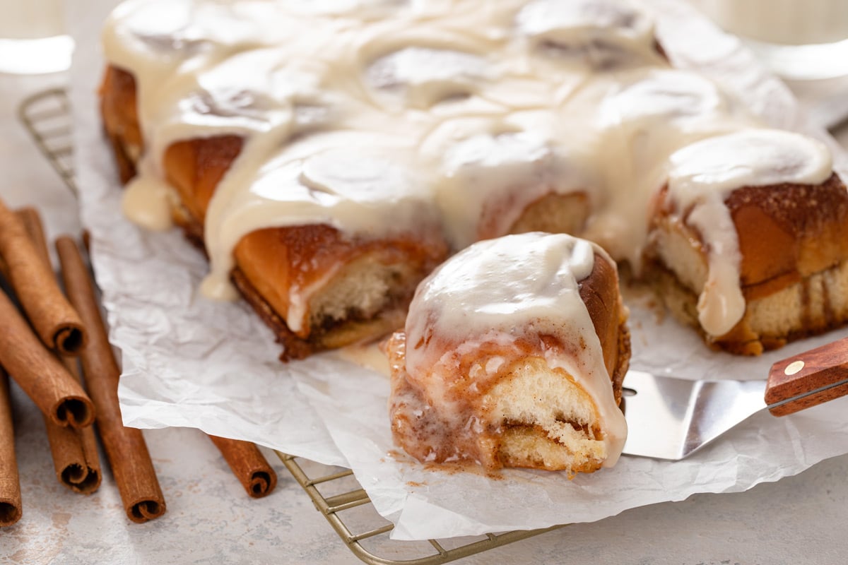 Cake server about to serve a cut hawaiian roll cinnamon roll.
