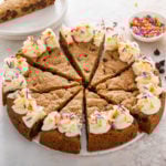 Sliced chocolate chip cookie cake topped with frosting and sprinkles.